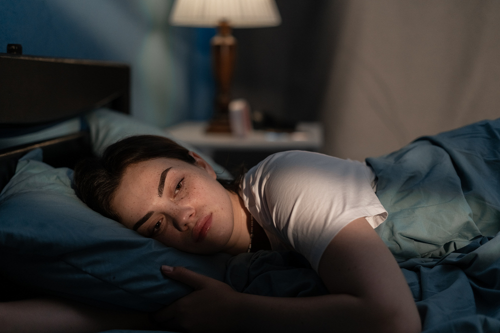 Erschöpfte junge Frau im Bett. / iStock/Andrii Lysenko Erschöpfte junge Frau im Bett.
